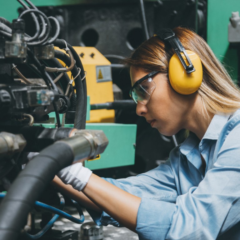 kobieta naprawia robota przemysłowego